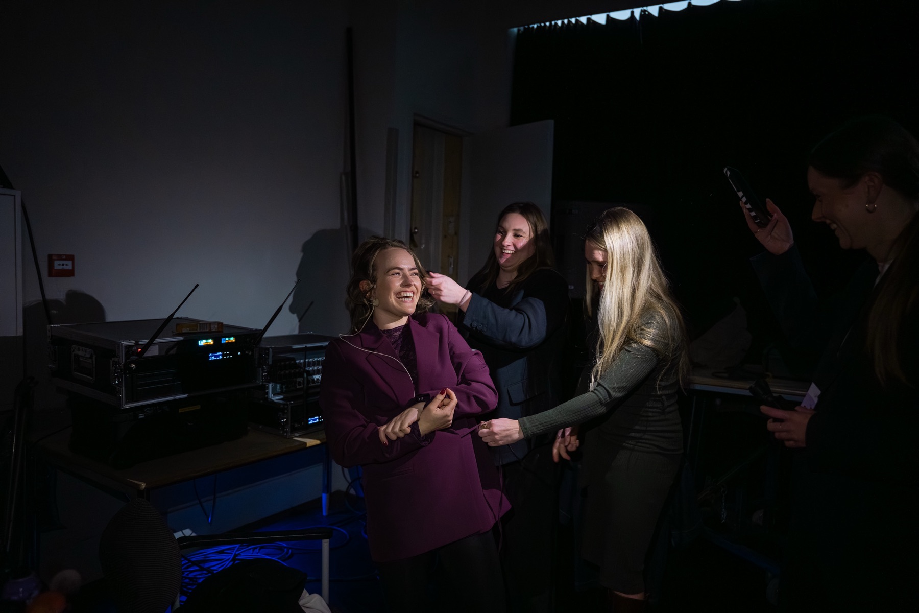 Robin Couprie backstage, lachend, terwijl haar microfoon wordt omgedaan